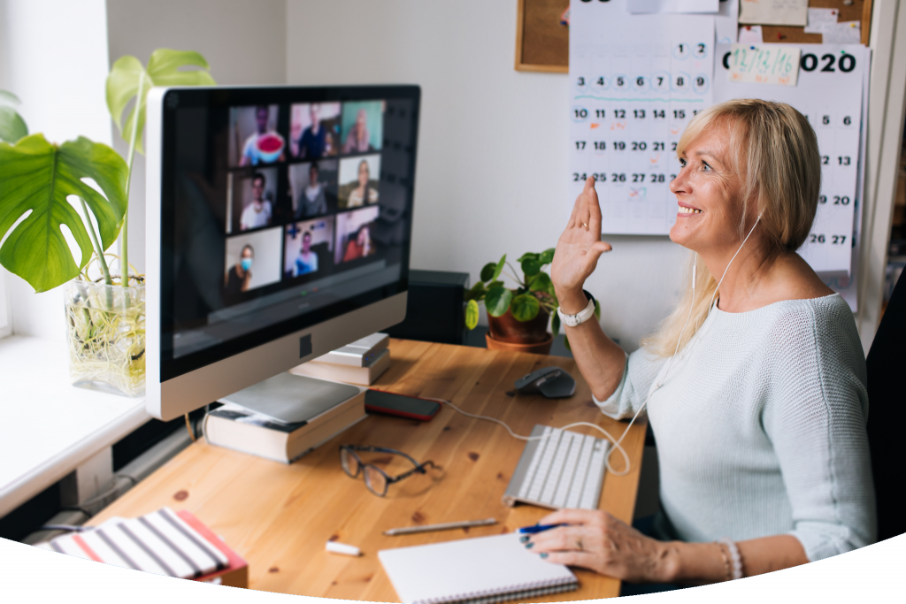Happy woman sitting at a computer with other trainees visible on screen in a group training